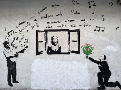 Marilyn Monroe in a window with two men serenading her. one with flowers and other singing.