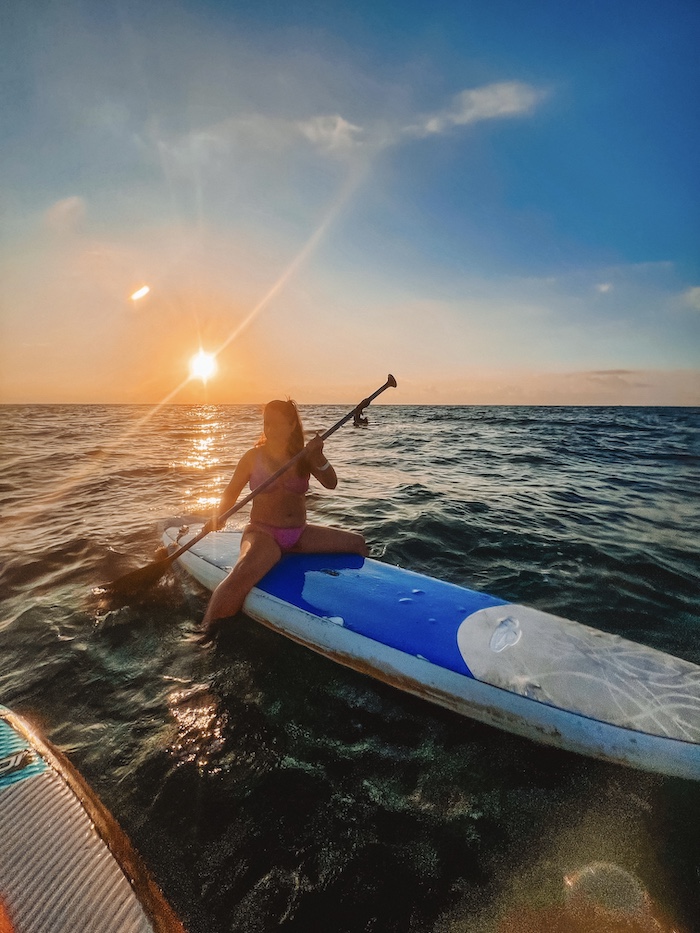 woman sitting on a SUP board during sunrise in the ocean - Playa del Carmen sunrise paddleboard Mexican Caribbean Coast