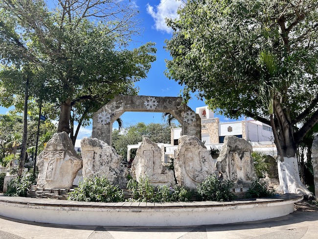 sign saying Tulum out of rock in front of trees and a blue sky - Mexican Caribbean Coast