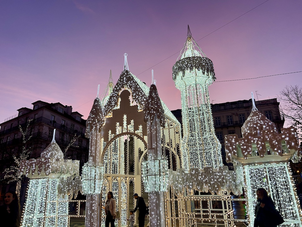 White and lit up Christmas castle in Lisbon during sunset time with a pnk and purple sky