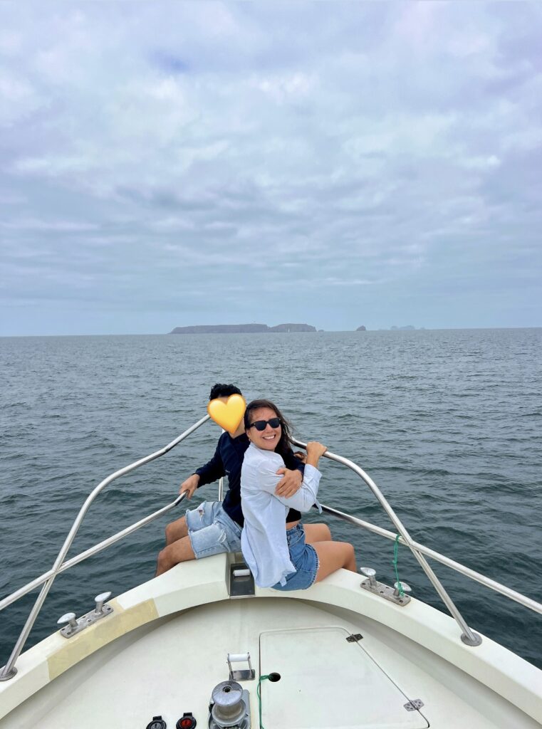 brunette couple sitting on a boat with Berlengas island in the background