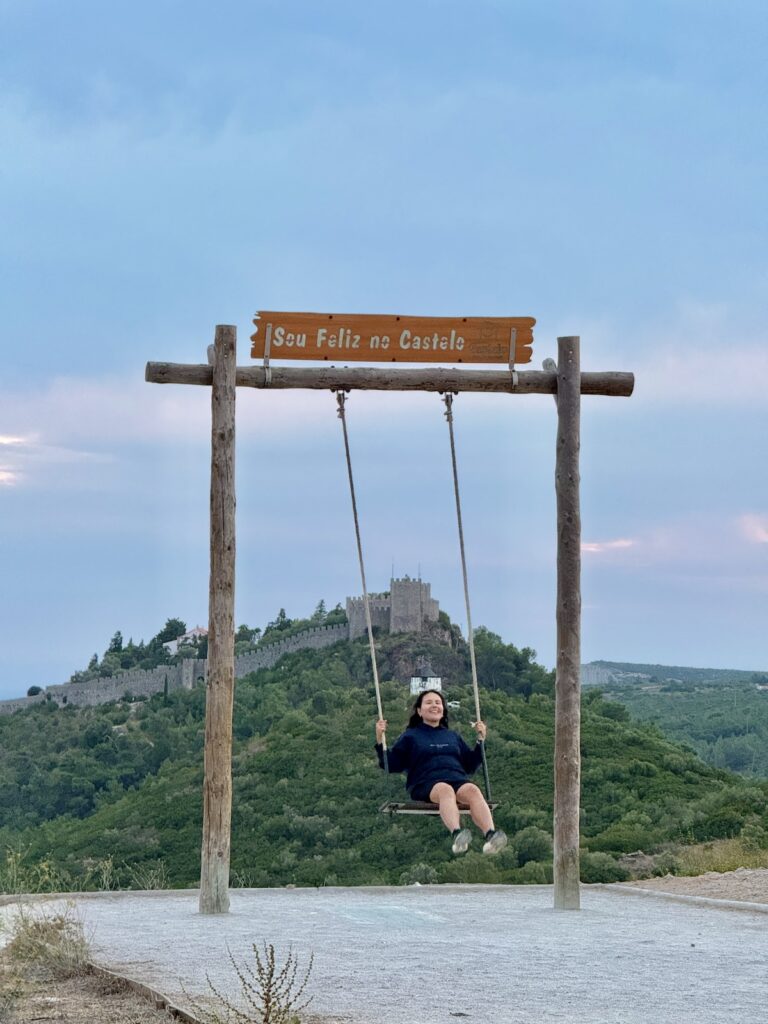 brunette swinging on a mountain across from one with a castle